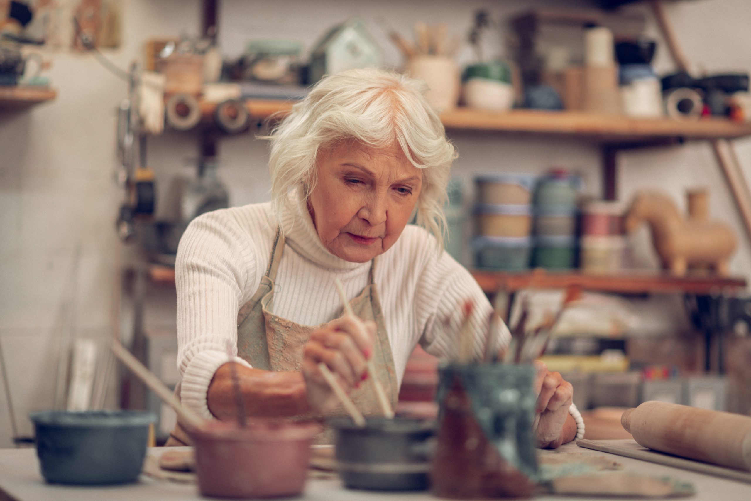 塗装を仕事としており、絵の具にブラシを入れる素敵な年配の女性。