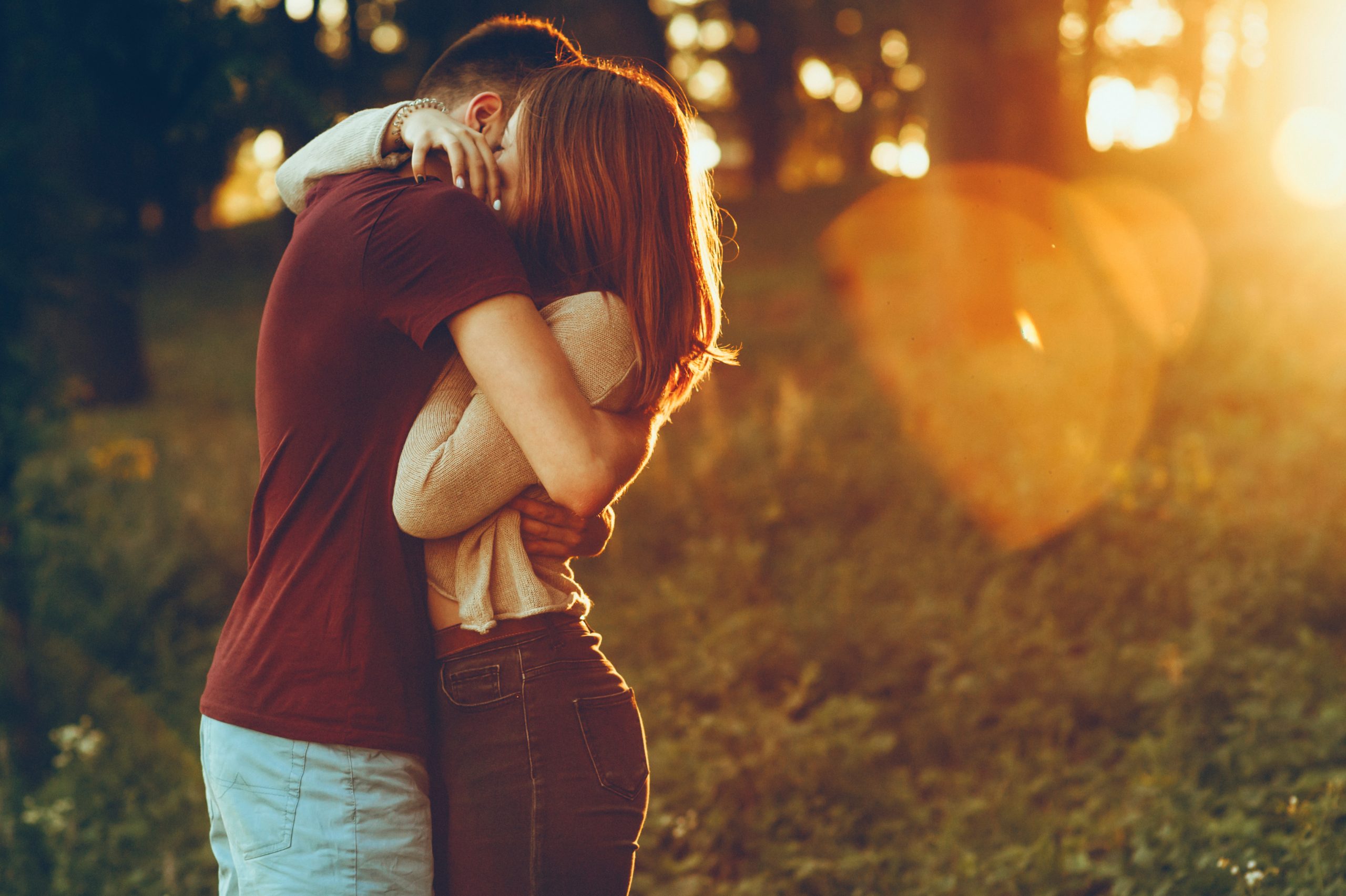 朝のデート中に日の出を背景に抱き合うカップル